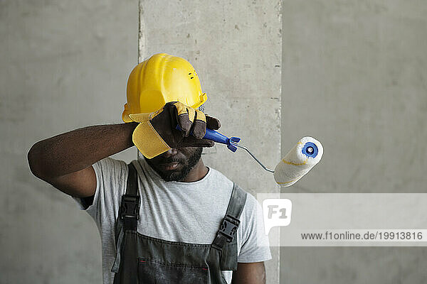 Tired construction worker wiping sweat at site