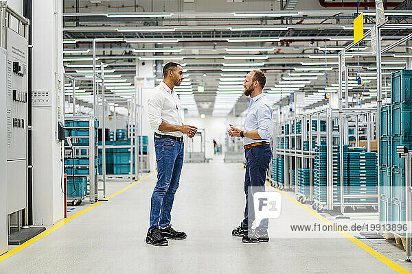 Two businessmen standing and talking in a factory
