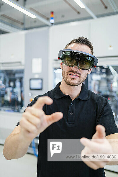 Technician wearing augmented reality glasses and gesturing in a factory