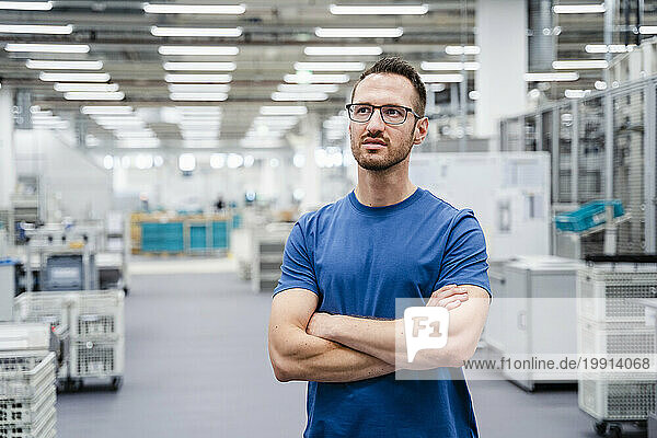 Employee standing in a factory with arms crossed