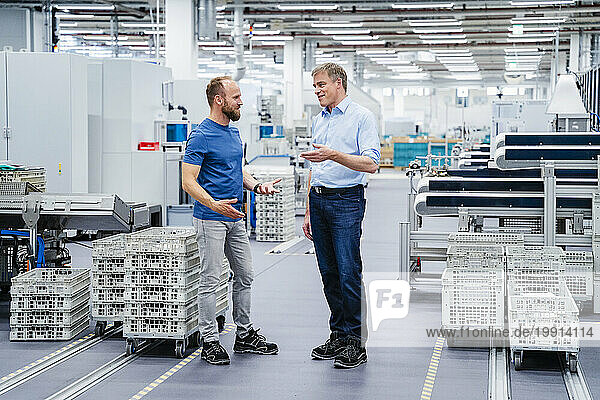 Businessman and employee talking in a factory