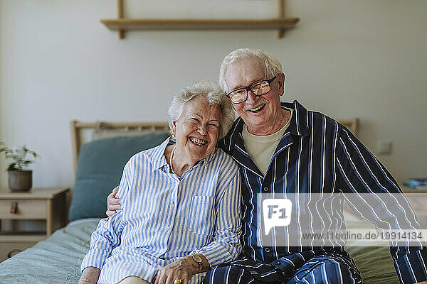 Happy senior couple sitting on bed together at home