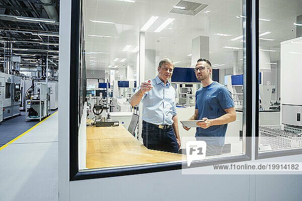 Businessman and employee with digital tablet having a discussion in a factory