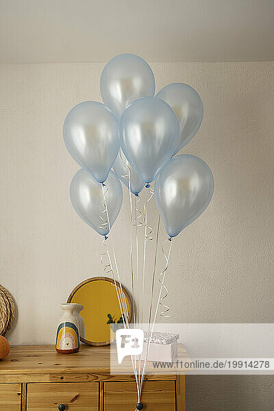 Balloons and gift box on cabinet at home