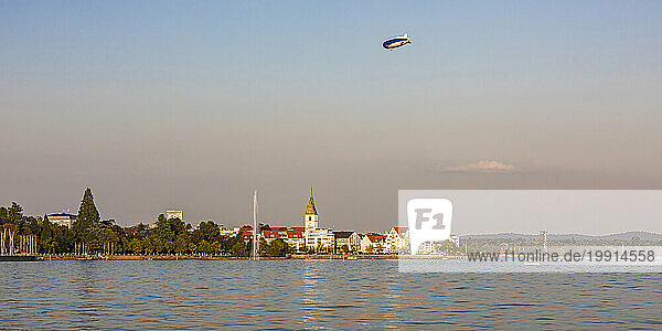 Germany  Baden-Wurttemberg  Friedrichshafen  Blimp flying over city on shore of lake Bodensee at dusk
