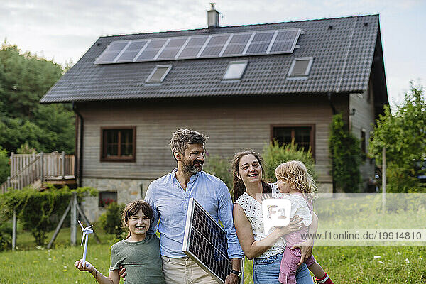 Young family having standing in front their family house with solar panels on the roof