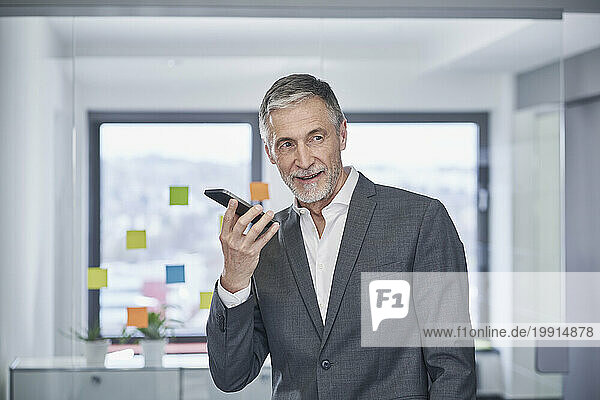 Happy senior businessman talking on mobile phone in office