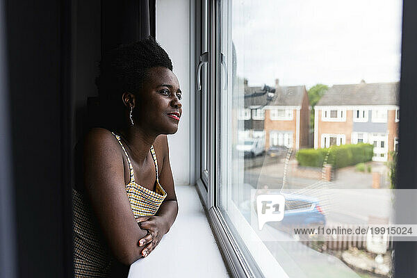 Contemplative woman looking out of window at home