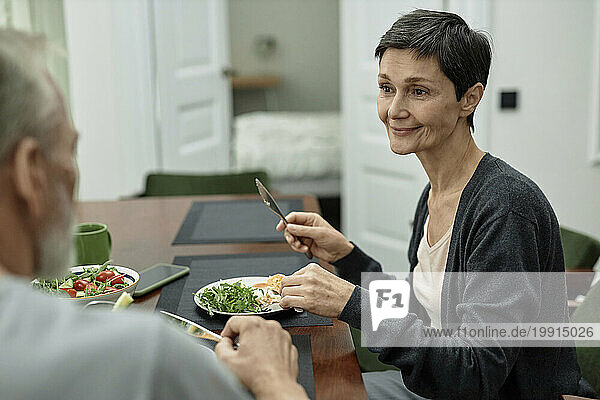 Adult woman looking at her husband while eating fried eggs and salad