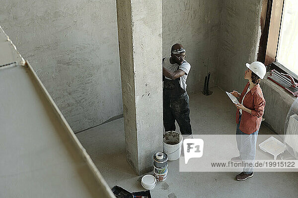 Engineer discussing over architectural column with coworker at construction site