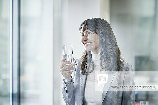 Happy businesswoman holding glass of water