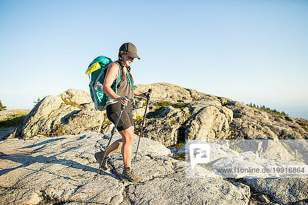 Side view of athletic woman backpacker on mountain summit