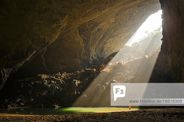 A caver illuminated by a sunbeam in Hang En Cave  Vietnam.