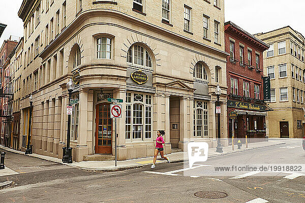 A young asian woman runs along streets of the North End of Boston  MA.