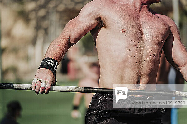 Muscular man with barbell during cross training competition