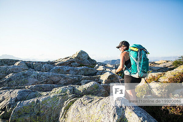 Side view of determined female hiker reaching mountain summit.