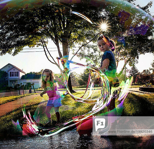 Young sisters looking through giant colorful bubble