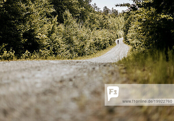 Cyclist rides his bike on remote gravel road katahdin woods and waters