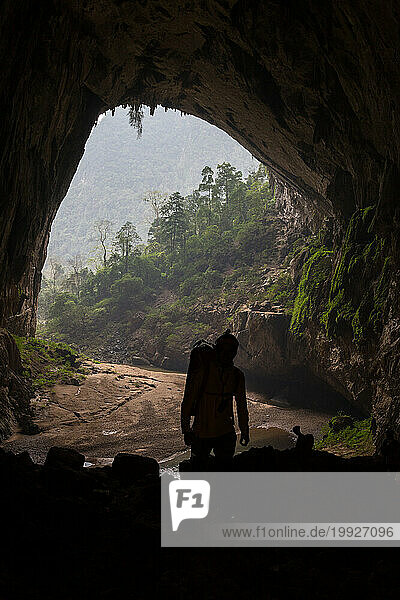 A silhouette of a cave explorer at the exit of Hang En  Phong Nha Ke Bang National Park  Vietnam.