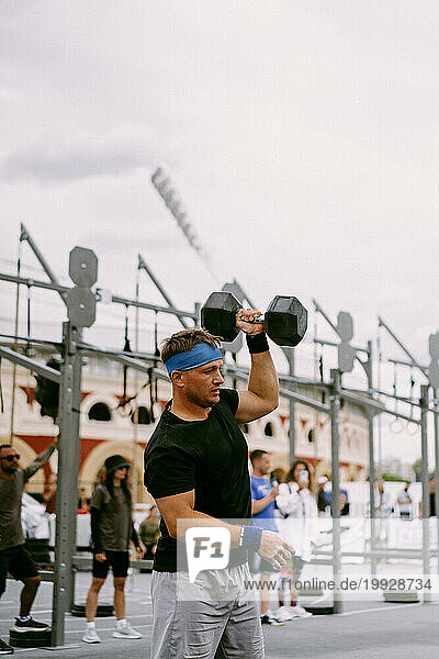 Men's CrossFit competition. Man with dumbbells.