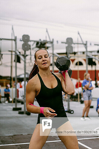 Women's CrossFit competition. Woman with dumbbells.