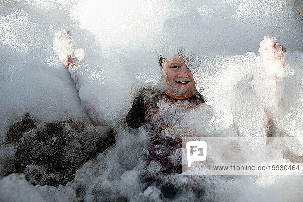 Child covered in pile of foam bubbles