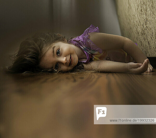 Beautiful little girl laying on floor in pajamas smiling