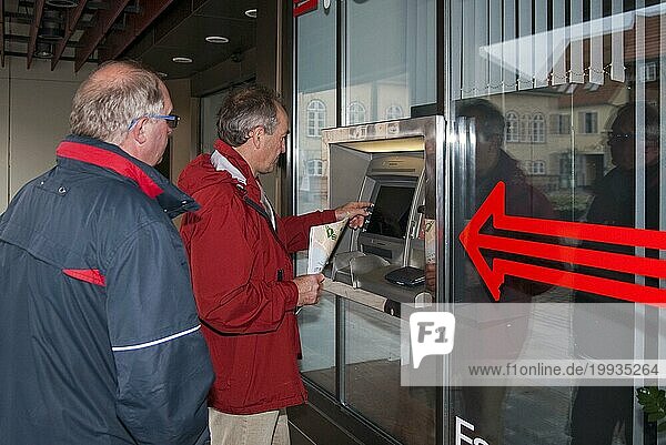 2 Männer stehen an einem Geldautomaten