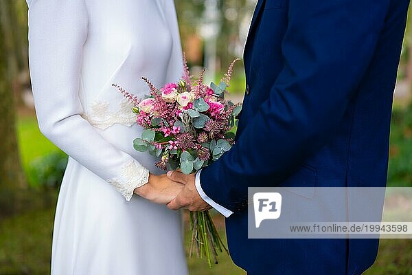 Detail der Hände bei der Hochzeit der glücklichen Braut und Bräutigam mit Blumen  Ehe Porträts