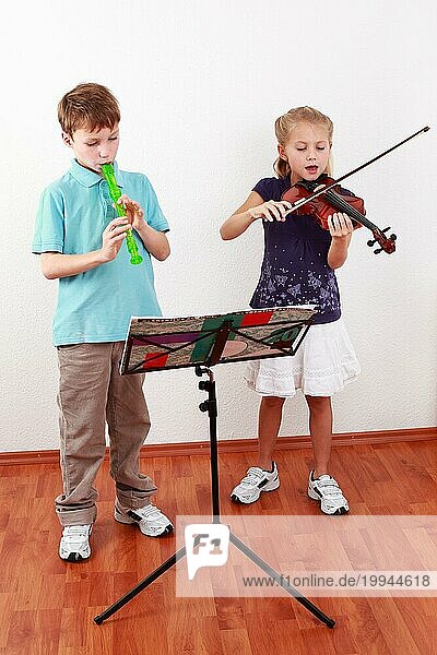 Niedliche Kinder spielen Flöte und Geige zusammen