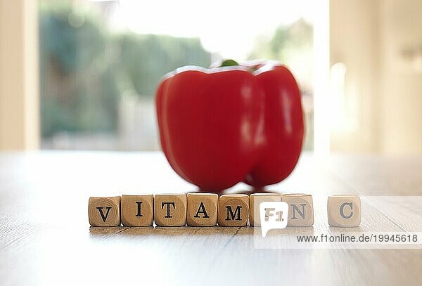Der Schriftzug Vitamin C mit einer frischen Biopaprika auf einem Küchentisch  selektiver Fokus im Vordergrund  Konzept der gesunden Ernährung