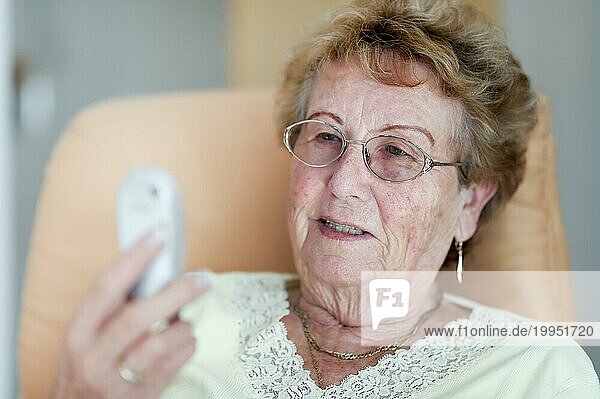 Rentnerin betrachtet vergnügt ihr Handy