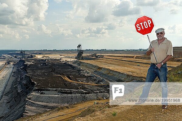 Mann steht am Rande des Tagebaues und hält ein STOP-Schild hoch