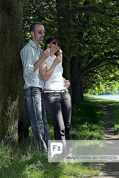 Junges Paar lehnt an einem Baum und ißt Eis