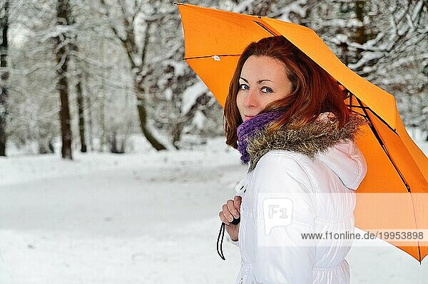 Junge Frau mit gelbem Schirm im Winterwald