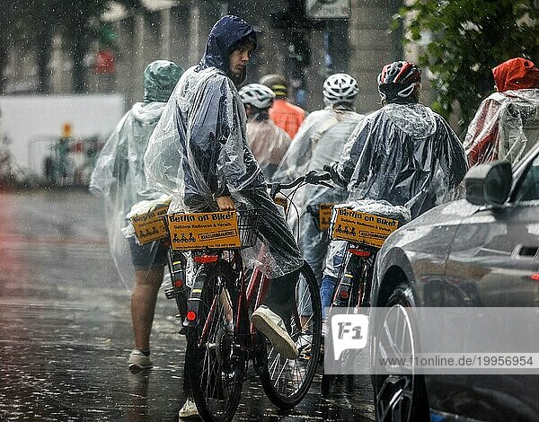 Touristen einer Berlin On Bike Fahrradtour schützen sich mit Regencapes vor starkem Regenfall  Berlin  23.06.2023