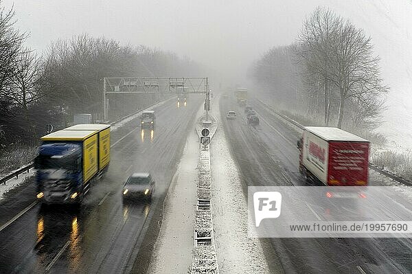 LKW und PKW auf einer Autobahn bei Schneetreiben und schlechter Sicht