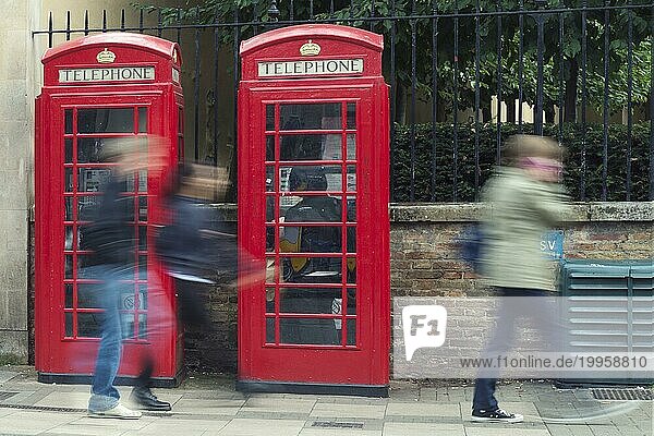 Schemen von Passanten vor 2 roten Telefonzellen. Großbritannien  Cambridceshire  Cambridge