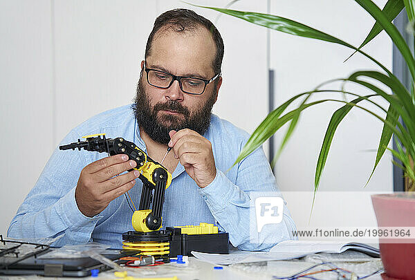 Engineer working on robotic arm at desk in office