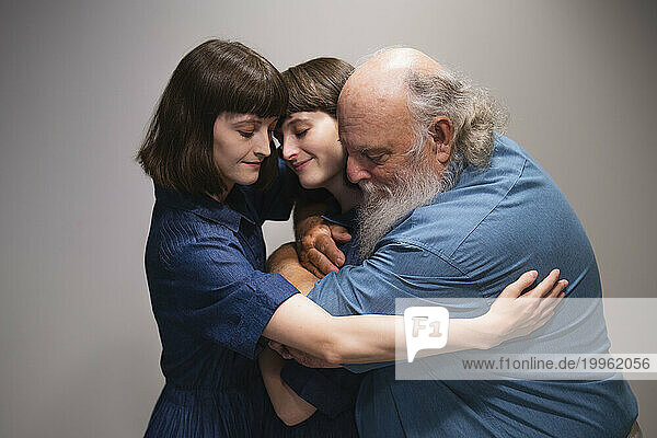 Loving father hugging two daughters
