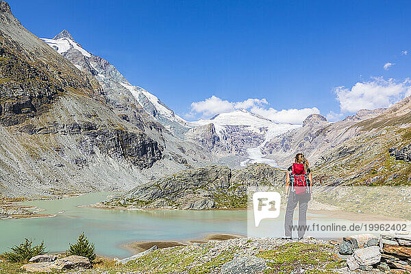 Woman standing on rock by Sandersee lake in front of mountains at Grossglockner  Austria