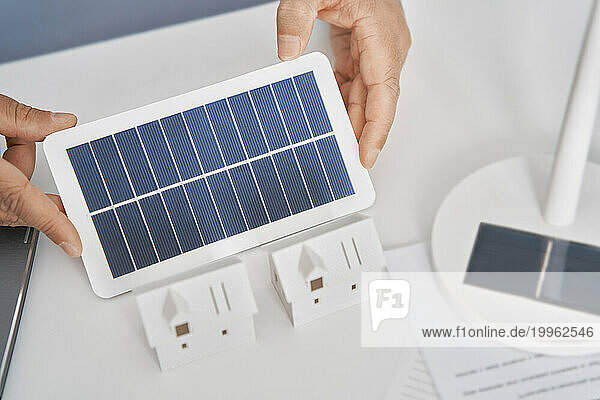 Architect holding solar panel at desk in office