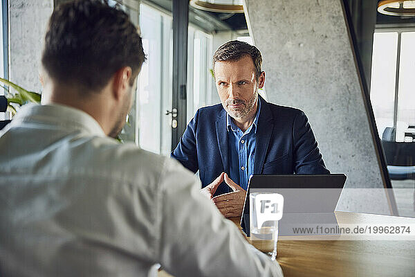 Serious recruiter taking interview of candidate at desk