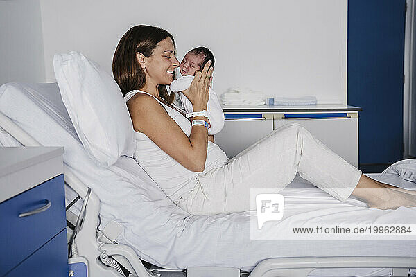 Loving mother embracing baby daughter on bed in hospital