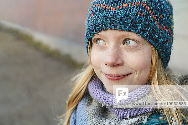 Smiling girl with blond hair wearing knitted hat