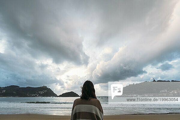 Young woman at Playa de la Concha under cloudy sky