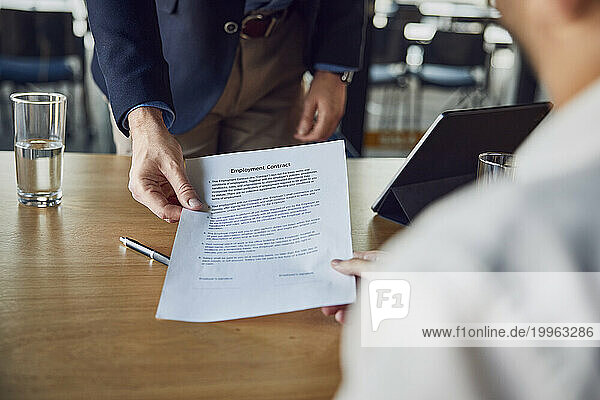 Recruiter giving contract to candidate at desk