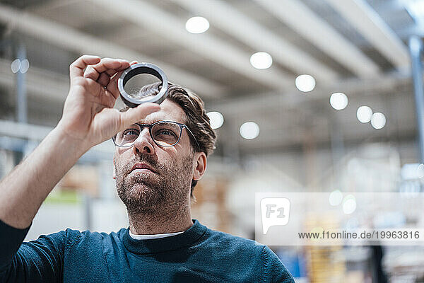 Businessman examining metal circle in industry