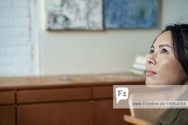 Thoughtful woman looking up in art studio