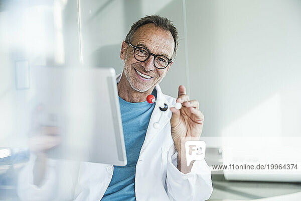 Happy senior man in lab coat holding tablet PC and molecular structure